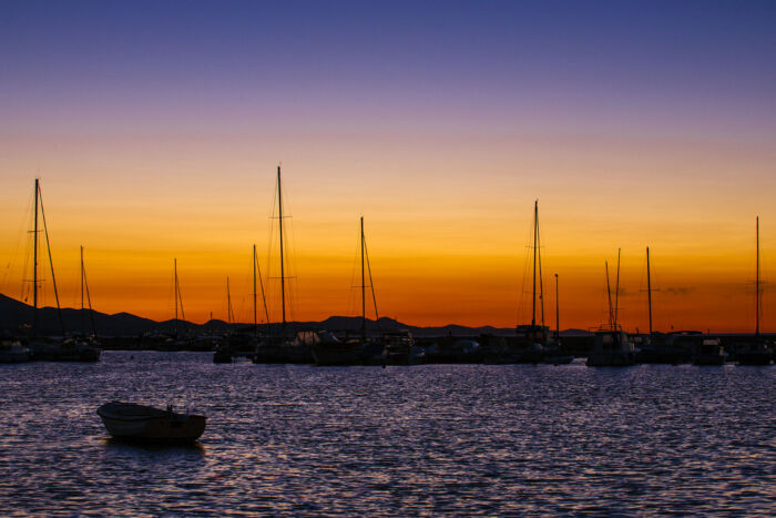 As the sun dips below the horizon, the sky over the harbor in Bibinje